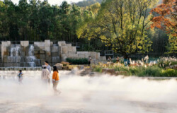 <a href="https://landscapearchitecturebuilt.com/staging/tangshan-ape-man-cave">Tangshan Ape Man Cave</a>, <br>Nanjing, China Landscape architecture project in China showing a large water feature with rough cut boulders and grasses along edge. A large sculptural stone water fall is beyond.