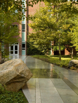 <a href="https://landscapearchitecturebuilt.com/keene-state-college">Keene State College: Natural Science Center Courtyard</a>, <br>Keene, NH, USA An image of a landscape architecture project at Keene State College, showing a paved pathway with a feature boulder to the left of walkway
