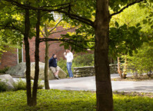 <a href="https://landscapearchitecturebuilt.com/keene-state-college">Keene State College: Natural Science Center Courtyard</a>, <br>Keene, NH, USA An image of a landscape architecture project at Keene State College, showing a tree grove with people resting on boulders in the background