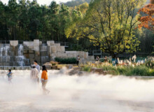 <a href="https://landscapearchitecturebuilt.com/tangshan-ape-man-cave">Tangshan Ape Man Cave</a>, <br>Nanjing, China Landscape architecture project in China showing a large water feature with rough cut boulders and grasses along edge. A large sculptural stone water fall is beyond.